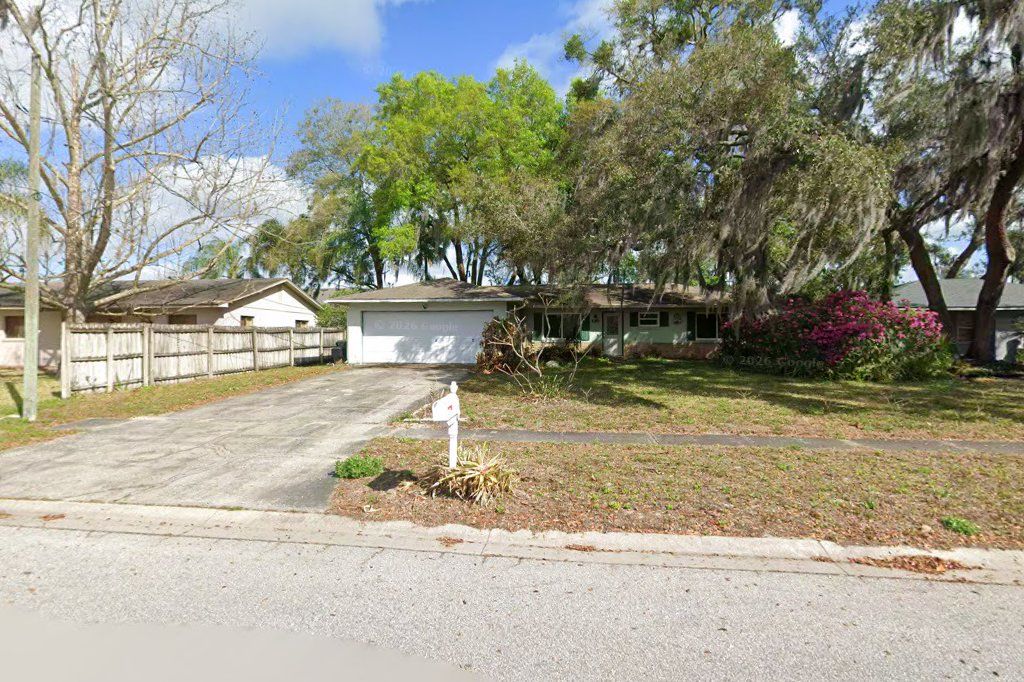 White one-story home with a wood fence and driveway on High Street, Oviedo